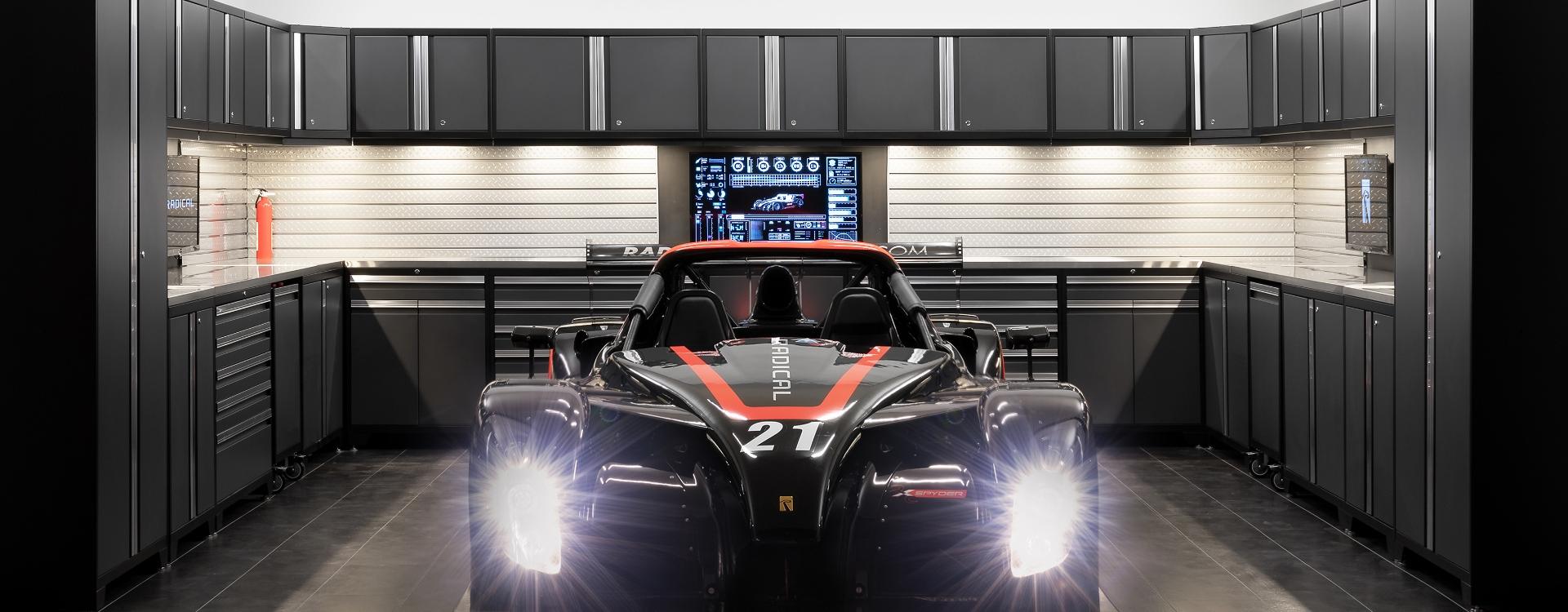 A race car parked in a well-lit garage, showcasing newageproducts garage cabinets in the background.