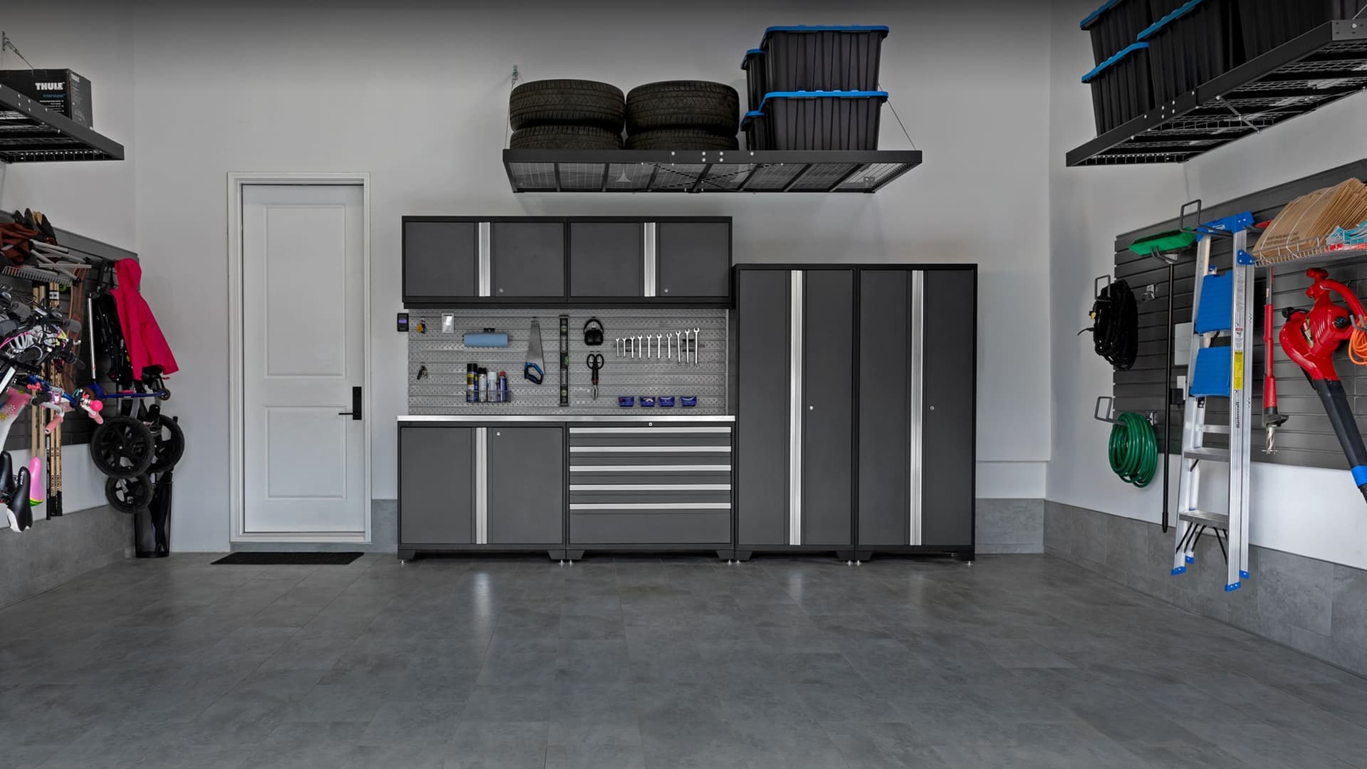 NewAge grey garage cabinets with a stainless-top workbench and an overhead tire rack