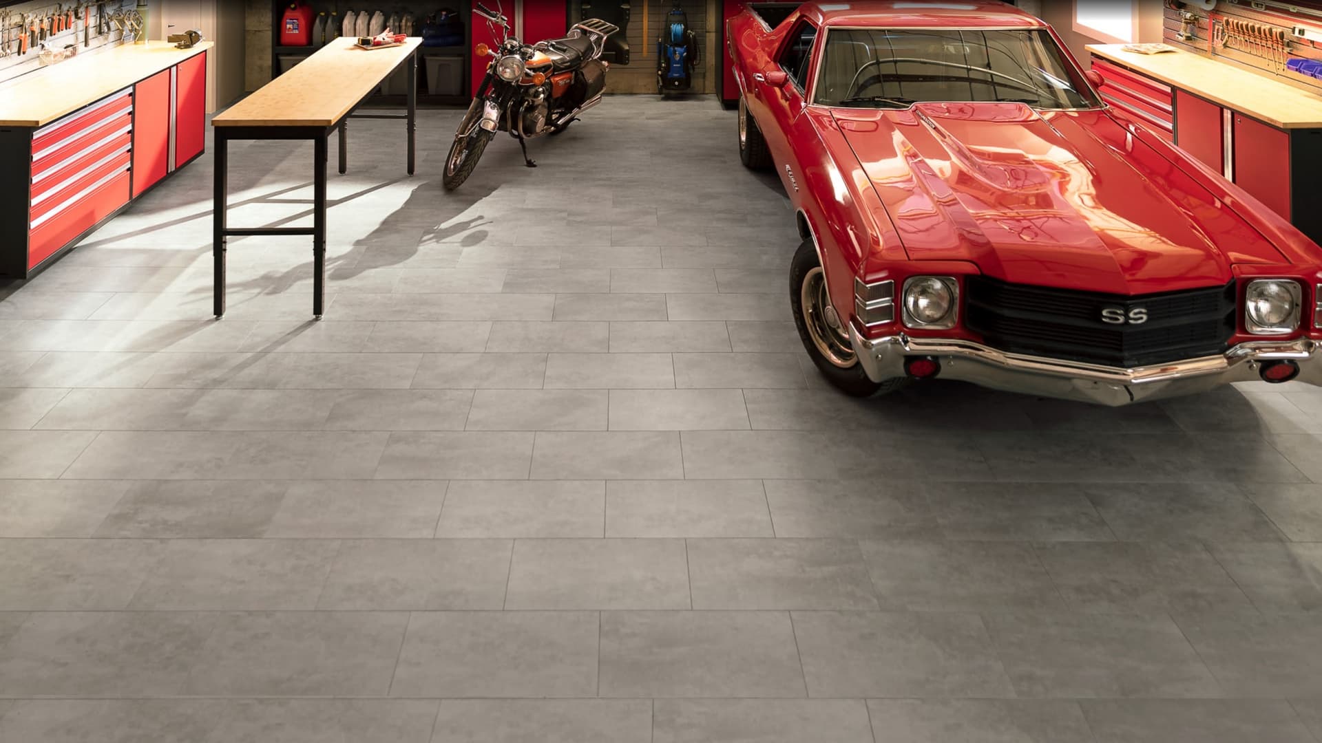 Close-up of grey NewAge garage floor tiles beneath the wheel of a red classic car