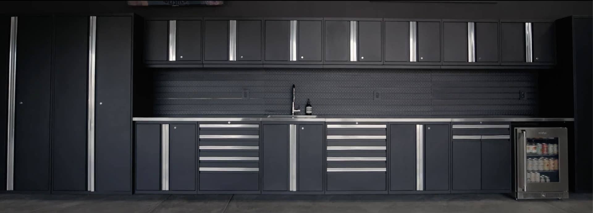 NewAge matte black outdoor kitchen run with a built-in gas grill, outdoor fridge and pizza oven