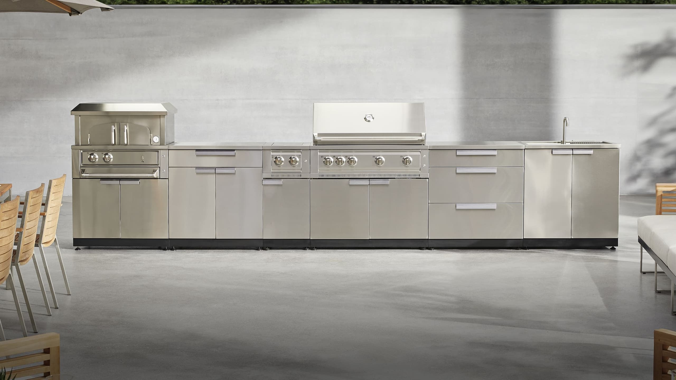 NewAge outdoor kitchen with stone-clad surrounds, a kamado grill and built-in gas grill