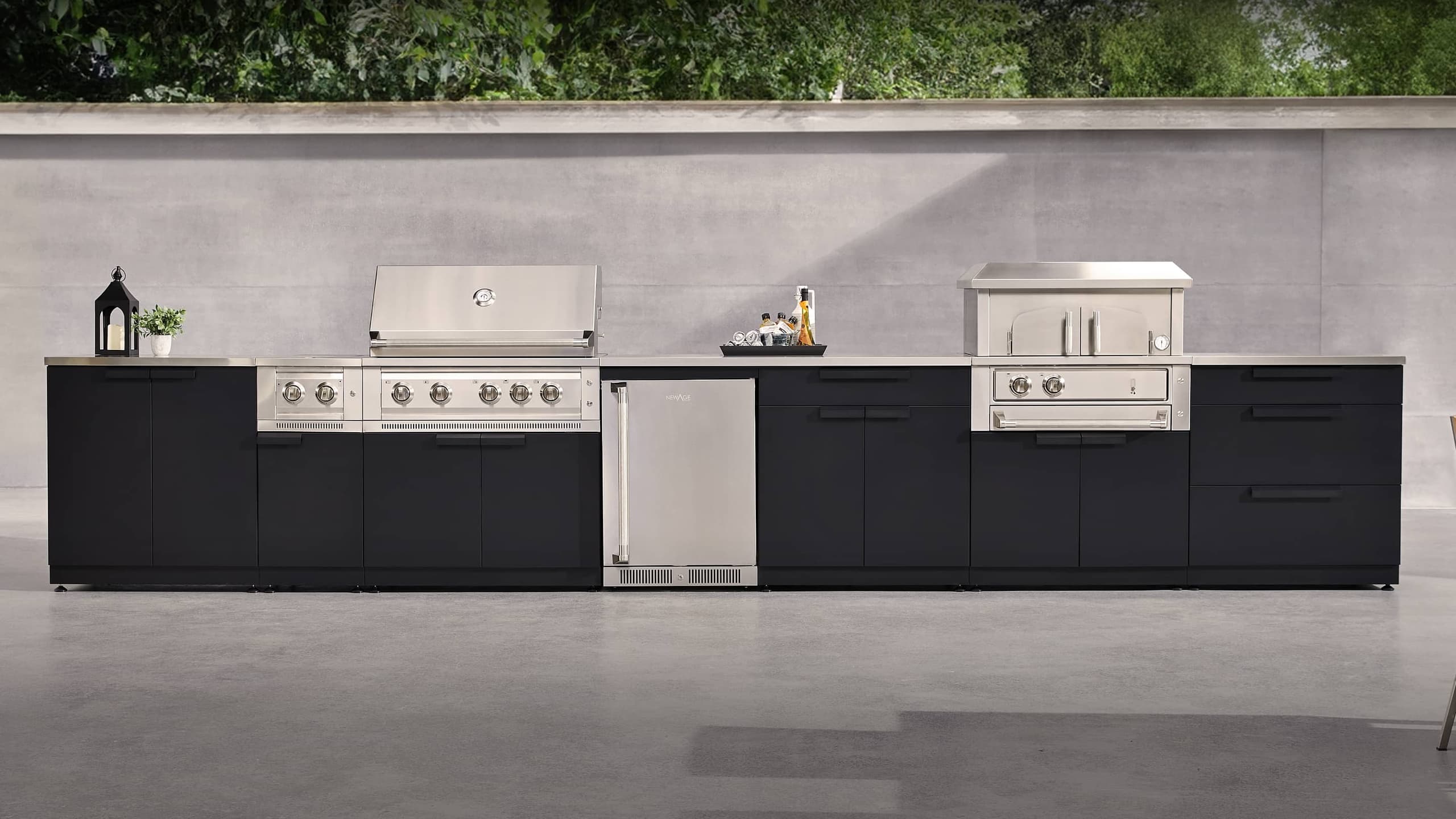 NewAge outdoor kitchen with stone-clad surrounds, a kamado grill and built-in gas grill